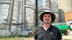 Artist Guido van Helten poses for a photo  in front of the grain elevator and silos where he is painting a large mural.