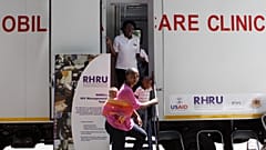 Bir kadın Güney Afrika'nın Johannesburg kentinde park halindeki bir mobil sağlık kliniğine giriyor.