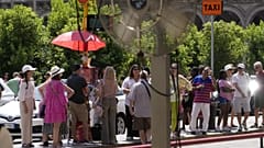 Touristen warten in der Sonne auf einen Bus in Mailand, Italien, Dienstag, 16. Juli 2024. 