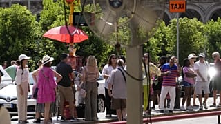 Touristen warten in der Sonne auf einen Bus in Mailand, Italien, Dienstag, 16. Juli 2024.