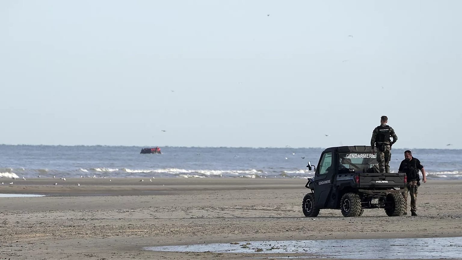 Gendarmes observam os migrantes num pequeno barco a partir da praia de Ecault, 4 de julho de 2025