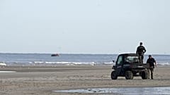 Gendarmen beobachten Migranten auf einem kleinen Boot am Strand von Ecault, 4. Juli 2025
