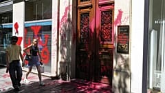 Άνθρωποι περπατούν δίπλα από το βανδαλισμένο γραφείο της ισραηλινής αεροπορικής εταιρείας El Al στο Παρίσι, με αντι-ισραηλινά γκράφιτι, την Πέμπτη 7 Αυγούστου 2025 στο Παρίσι. (AP Photo/Michel Euler)
