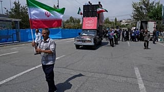 Um adorador segura uma bandeira iraniana no início de um protesto anti-EUA e anti-israelita após as orações de sexta-feira em Teerão, Irão, sexta-feira, 25 de julho de 2025.