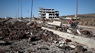 Δρούζοι πολιτοφύλακες περνούν μπροστά από το σημείο ενός υποτιθέμενου χτυπήματος του ισραηλινού στρατού στον κεντρικό δρόμο έξω από την πόλη Suwayda, 25 Ιουλίου 2025.