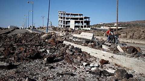 Druze militiamen ride past the site of an alleged Israeli army strike on the main road outside the Druze-majority town of Suwayda, 25 July, 2025