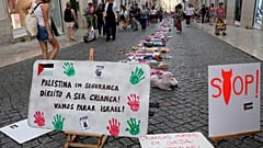 Un grupo de personas pasa junto a una instalación de ropa y juguetes infantiles en la Rua do Carmo, en el centro de Lisboa, para llamar la atención sobre la situación de los niños en Gaza.
