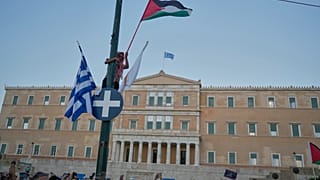 متظاهر يلوح بعلم فلسطيني خلال مظاهرة ضد الحرب في قطاع غزة، وإجراءات إسرائيل بشأن توزيع الغذاء خارج البرلمان اليوناني في وسط أثينا، الخميس 24 يوليو/ تموز 2025.
