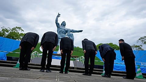 Visitors bow to pray at the Nagasaki Peace Statue ahead of a ceremony to mark the 80th anniversary of the atomic bombing at Nagasaki Peace Park in Japan, Friday, Aug. 8, 2025.