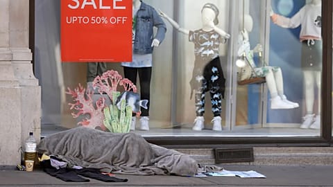 A homeless person sleeps in front of a closed clothing shop in London, 14 May, 2020 