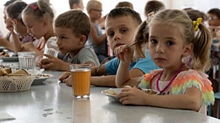 Des enfants d'un orphelinat de la région de Donetsk mangent un repas dans un camp à Zolotaya Kosa, la colonie sur la mer d'Azov, région de Rostov, sud-ouest de la Russie, le 8 juillet 2022.