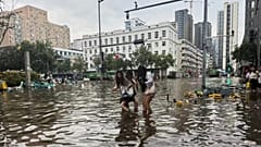 Frauen waten durch eine überschwemmte Straße nach heftigen Regenfällen in Zhengzhou, 7. August 2025