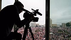 Belaruslu muhalefet destekçileri Minsk'teki Bağımsızlık Meydanı'nda miting yaparken bir kameraman çalışıyor, 23 Ağustos, 2020