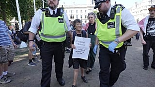 A woman is detained by police officers as supporters of Palestine Action take part in a mass action in Parliament Square, on Saturday Aug. 9, 2025.