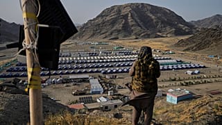 مقاتل من طالبان يقف على تل يطل على مخيم يسكنه لاجئون أفغان أعيدوا من باكستان ، بالقرب من الحدود الباكستانية الأفغانية ، في تورخام ، أفغانستان ، 31 مايو / أيار 2025. 
