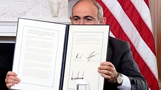 Nikol Pashinyan örmény miniszterelnök tartja az aláírt háromoldalú megállapodást Ilham Aliyev azerbajdzsáni elnökkel és Donald Trump amerikai elnökkel tartott ünnepségen, 2025. augusztus 8-án.