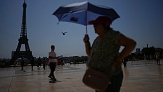 Des gens se promènent sur la place du Trocadéro, près de la tour Eiffel, pendant une vague de chaleur, le 2 juillet 2025, à Paris.