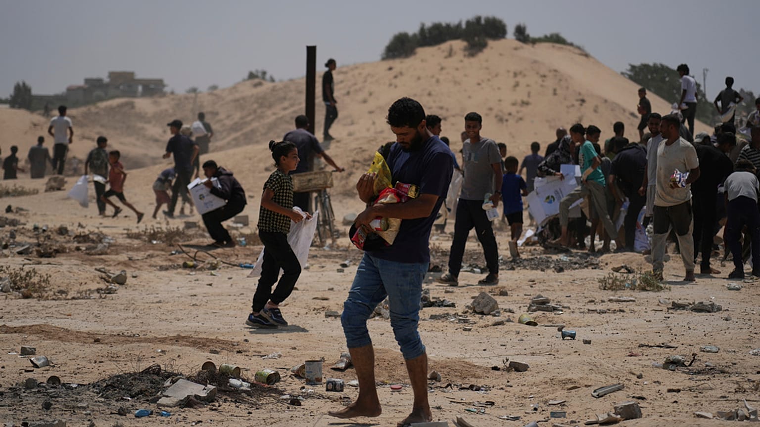 الفلسطينيون يجمعون حزم مساعدات إنسانية من الإمارات العربية المتحدة بعد أن تم إنزالهم جوا إلى دير البلح, في وسط قطاع غزة, يوم السبت, أغسطس. 9, 2025