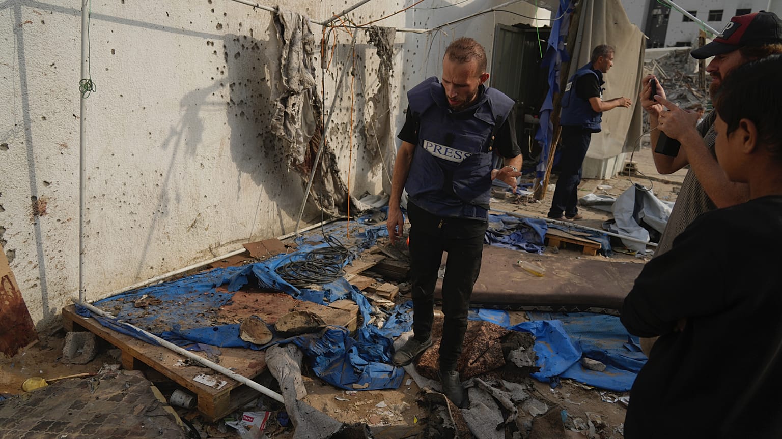 فلسطينيون يتفقدون الخيمة المدمرة التي قُتل فيها الصحفيون، بمن فيهم مراسلا الجزيرة أنس الشريف ومحمد قريقع، في غارة جوية إسرائيلية في مدينة غزة, الاثنين 11 أغسطس/ آب 2025.