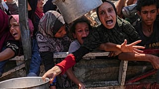 فلسطينيون يحاولون الحصول على طعام في مطبخ مجتمعي بمدينة غزة، 4 آب 2025.     