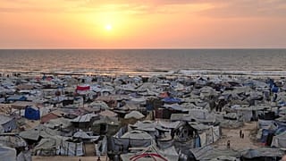 Tendas que albergam palestinianos deslocados enchem a praia na cidade de Gaza, enquanto o sol se põe sobre o Mar Mediterrâneo, domingo, 10 de agosto de 2025.