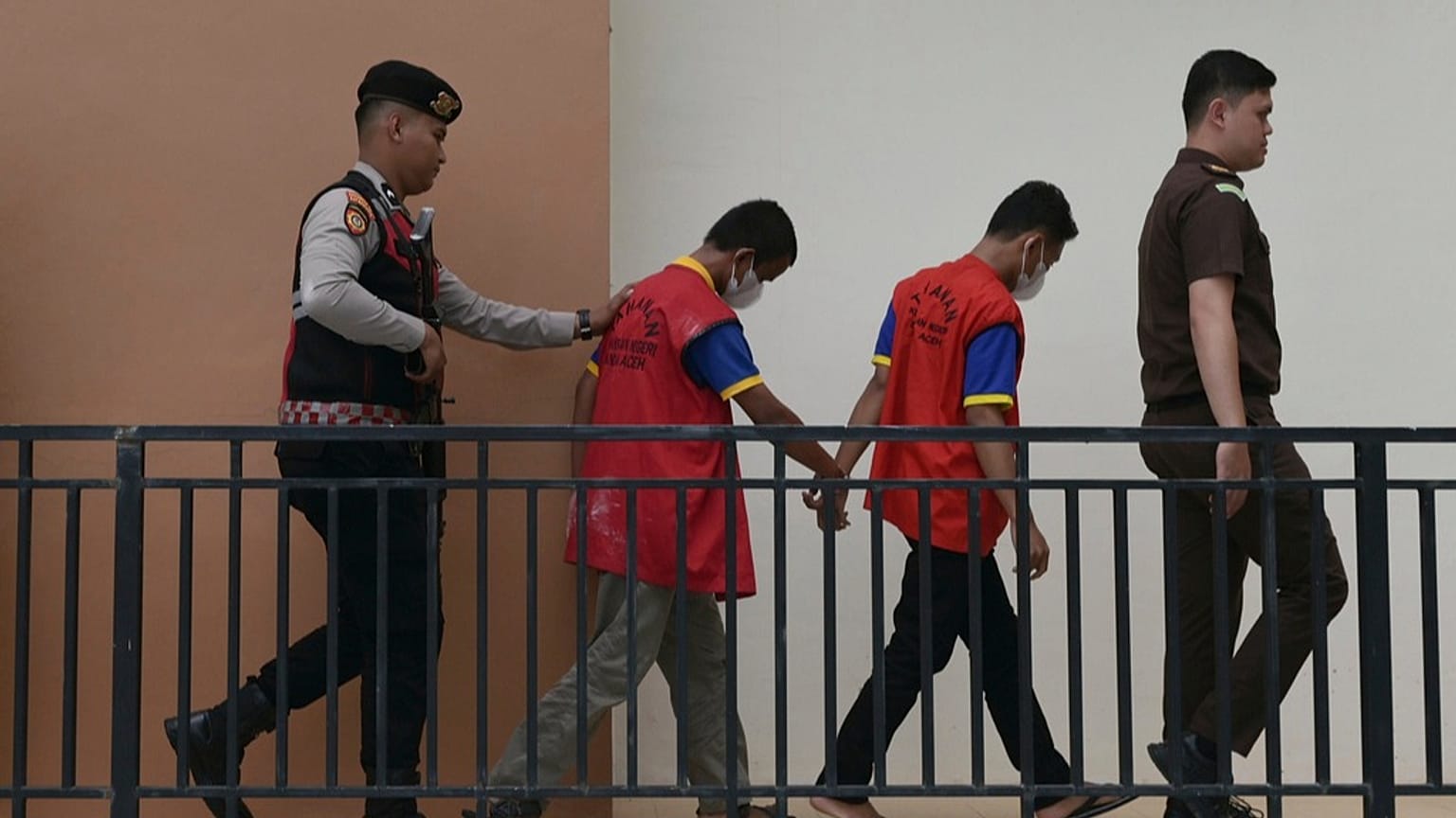 ضابط شرطة ومدعٍ عام يقتادان شابين متهمين بالمثلية إلى محكمة شرعية في باندا آتشيه بإندونيسيا، الاثنين 11 أغسطس 2025.