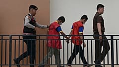ضابط شرطة ومدعٍ عام يقتادان شابين متهمين بالمثلية إلى محكمة شرعية في باندا آتشيه بإندونيسيا، الاثنين 11 أغسطس 2025.