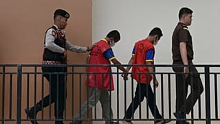ضابط شرطة ومدعٍ عام يقتادان شابين متهمين بالمثلية إلى محكمة شرعية في باندا آتشيه بإندونيسيا، الاثنين 11 أغسطس 2025.