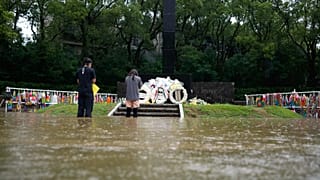 Deux personnes prient dans l'eau jusqu'aux genoux au mémorial en l'honneur des victimes du bombardement atomique de Nagasaki, le 9 août 2025.