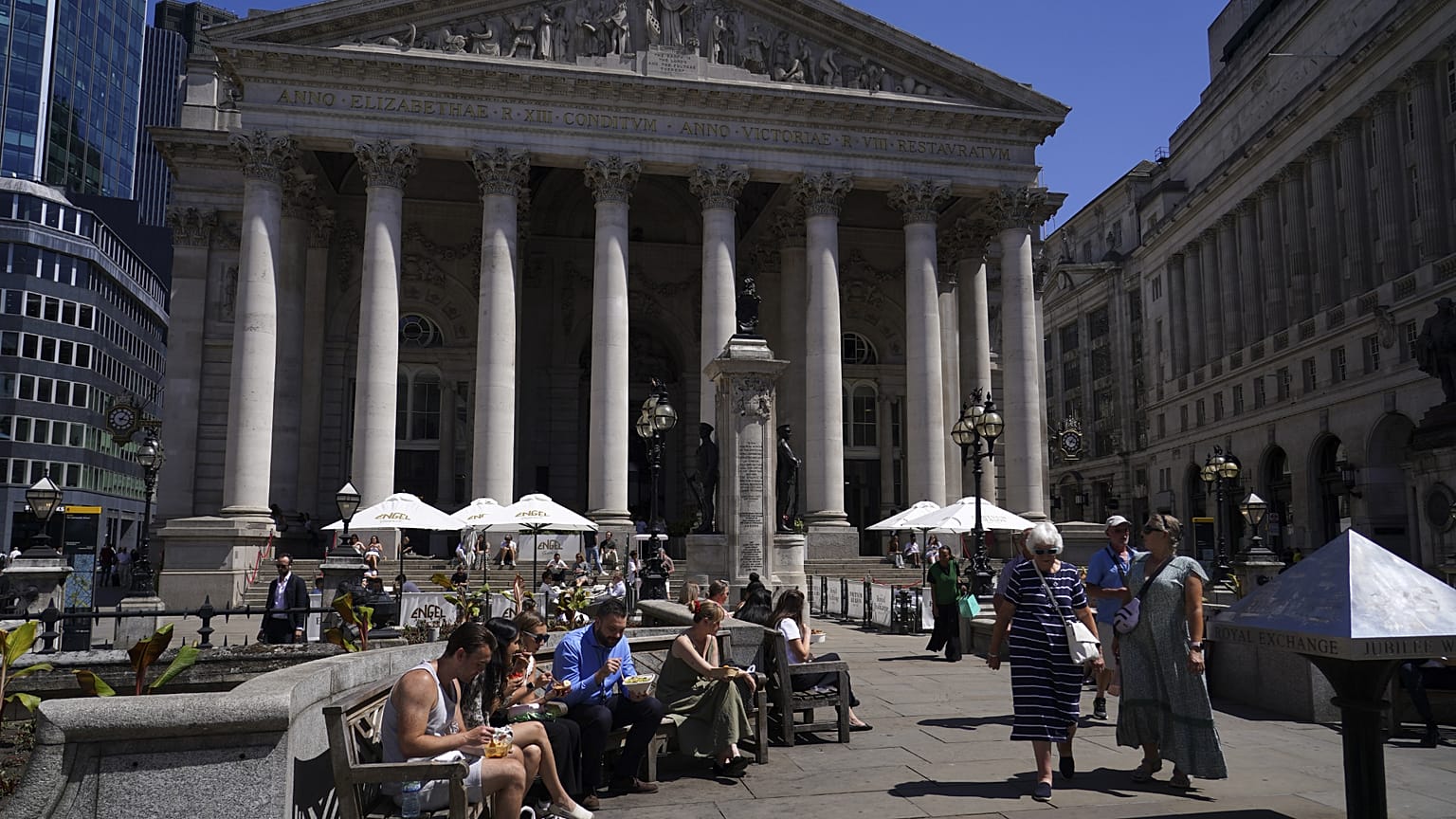People sit in the sun next to the Bank of England in London. 11 July 2025.
