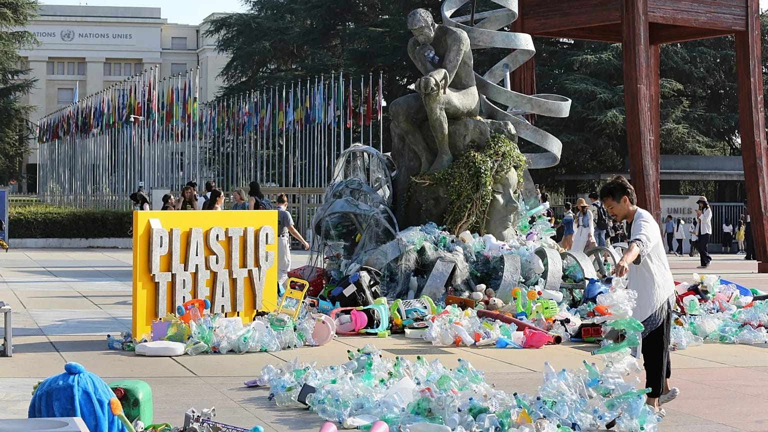 Kanadalı sanatçı ve aktivist Benjamin Von Wong, sağda, Cenevre'deki Birleşmiş Milletler ofisinin önünde tasarladığı büyük bir heykelin üzerine plastik atık yığınları yığıyor.