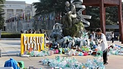 Kanadalı sanatçı ve aktivist Benjamin Von Wong, sağda, Cenevre'deki Birleşmiş Milletler ofisinin önünde tasarladığı büyük bir heykelin üzerine plastik atık yığınları yığıyor.
