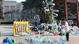Benjamin Von Wong, a la derecha, artista y activista canadiense, amontona residuos plásticos en una gran escultura que ha diseñado frente a la ONU en Ginebra.