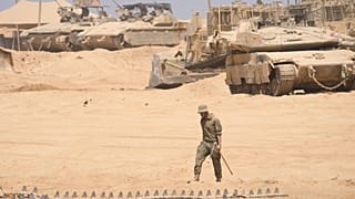 Bir İsrail askeri, Gazze'nin sınırındaki bir bölgede tankların önünde beklerken, 29 Temmuz 2025
