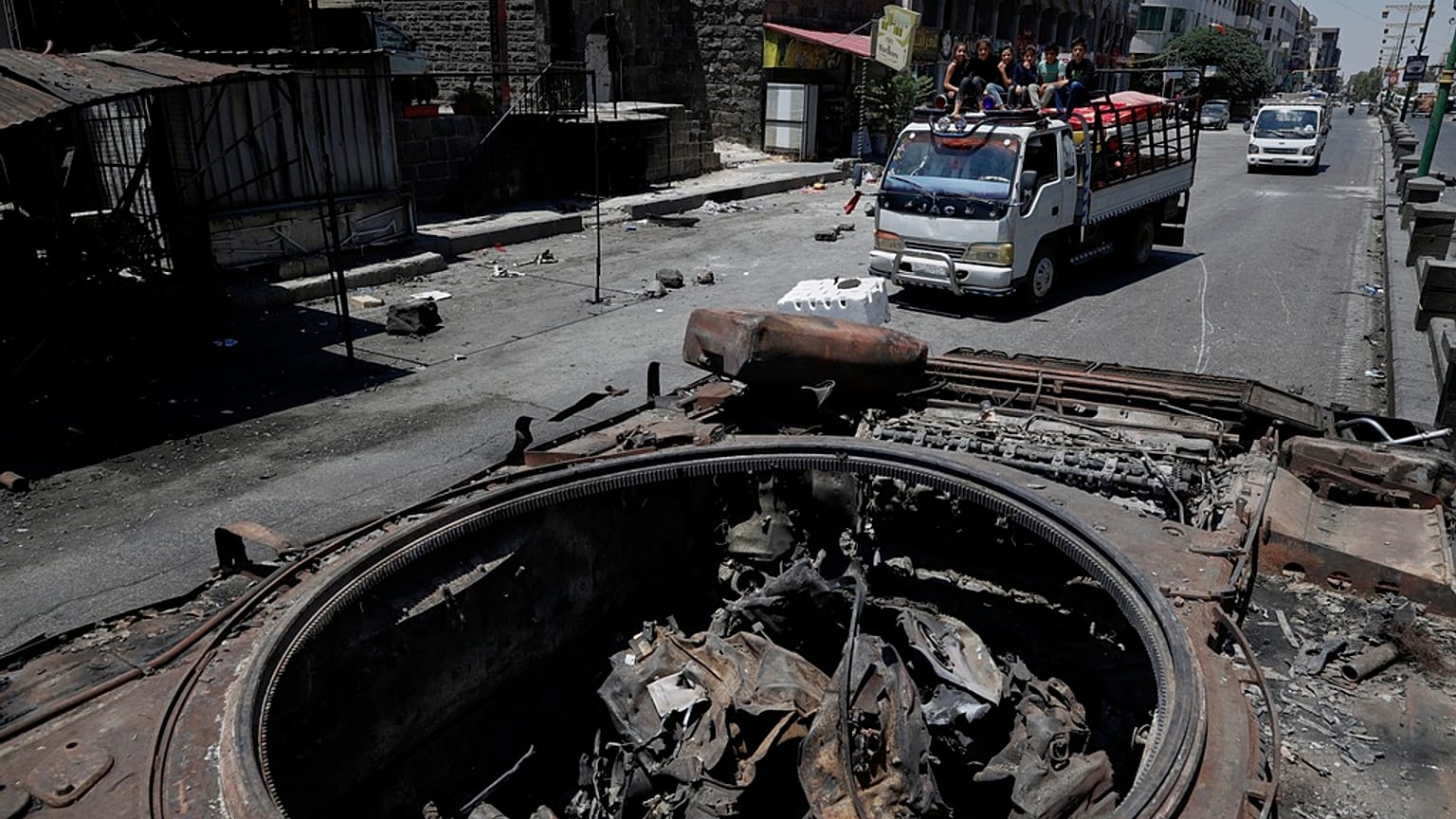 سيارة فان تحمل سكانًا تمر بجانب مركبة عسكرية مدمرة في أعقاب الاشتباكات الطائفية التي اندلعت الأسبوع الماضي في بلدة السويداء ذات الأغلبية الدرزية في سوريا، الجمعة 25 يوليو/تموز