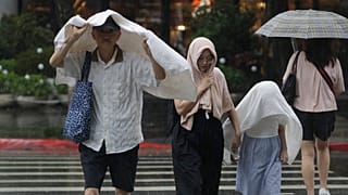 Pessoas caminham à chuva em Taipé, Taiwan, segunda-feira, 7 de julho de 2025, durante a passagem do tufão Danas por Taiwan. (AP Photo/Chiang Ying-ying)