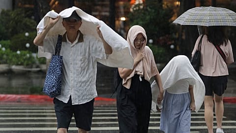 People walk in the rain in Taipei, Taiwan, Monday, July 7, 2025, as Typhoon Danas was passing through Taiwan. (AP Photo/Chiang Ying-ying)