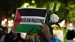 Bir gösterici, 12.08.2025'te Mexico City'de, Gazze'de İsrail hava saldırısında öldürülen gazeteciler için düzenlenen bir nöbette, "Meksika Filistin'in Yanında" yazılı bir pankart ve bir çiçek tutuyor.