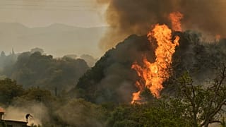 Un uomo lotta contro il fuoco mentre si avvicina a una casa durante un incendio selvaggio a Vounteni, alla periferia di Patrasso, nella Grecia occidentale, mercoledì 13 agosto 2025. 
