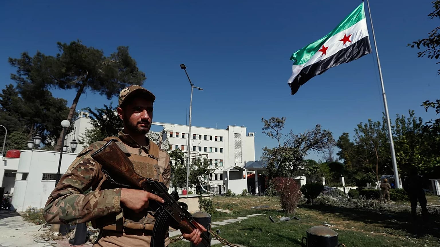 Syrian soldiers raise the Syrian national flag in front of the Syrian Defence Ministry building in Damascus, 19 July, 2025