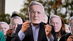 Varios partidarios del expresidente colombiano Álvaro Uribe muestran caretas de su rostro ante el tribunal donde fue declarado culpable de manipulación de testigos y soborno.