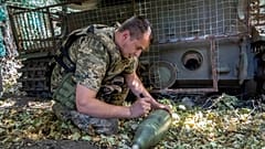 Az ukrán 30. gépesített dandár egyik katonája üzenetet ír egy ágyúgránátra, amelyet az orosz állások felé lőnek a frontvonalon, az ukrajnai Harkiv közelében szerdán, augusztus 29-én. 
