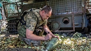 Un soldat de la 30e brigade mécanisée d'Ukraine écrit un message sur un obus d'obusier pour tirer en direction des positions russes sur la ligne de front près de Kharkiv, Ukraine, mercredi, Aug.