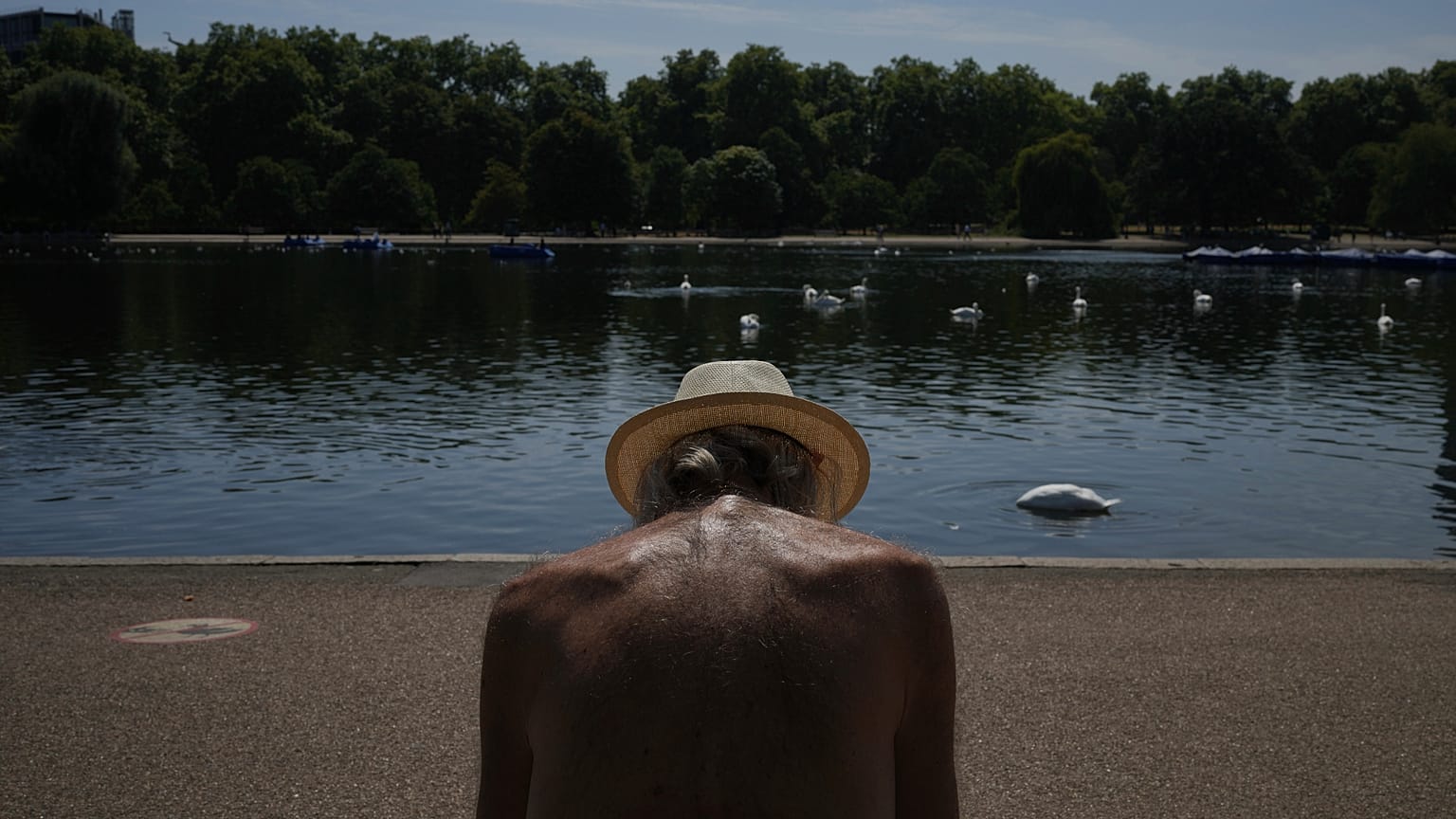 A man sits in the sun at a park in London as parts of the United Kingdom face a heat wave in August 2025.