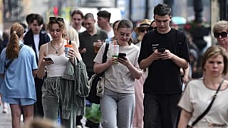 Pedoni guardano i loro telefoni mentre camminano a San Pietroburgo, in Russia, il 14 luglio 2025.