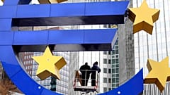Trabajadores cambian las luces del tubo de la escultura del euro frente al Banco Central Europeo en Fráncfort,
