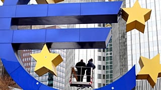 Trabajadores cambian las luces del tubo de la escultura del euro frente al Banco Central Europeo en Fráncfort,