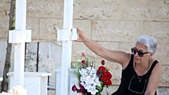 FILE: A woman touches the photo at the grave of her relative, killed in the 1974 Turkish invasion of Cyprus, in Nicosia, 20 July 2024