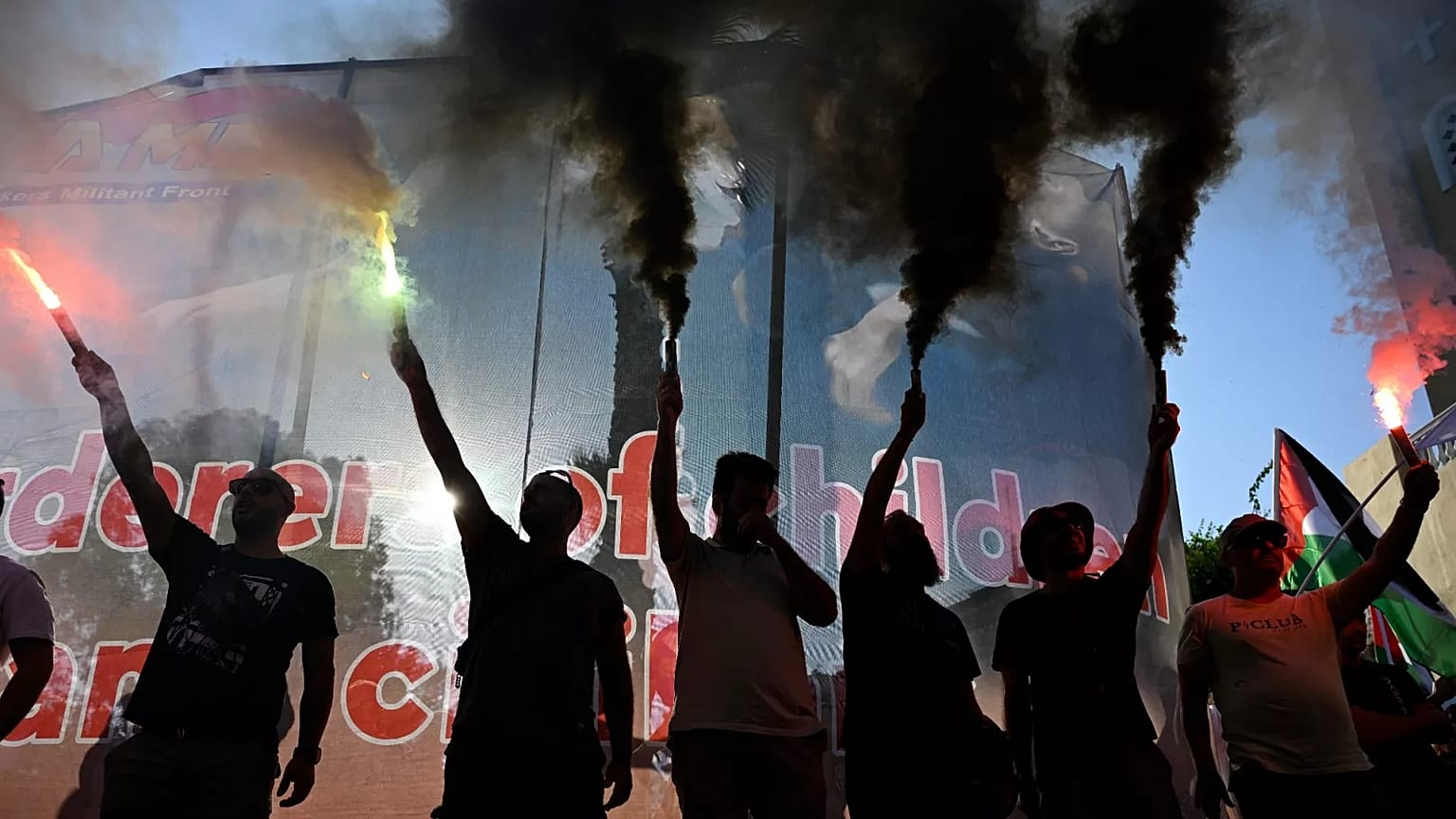 Protesters hold flares during a rally to protest the arrival of a cruise ship with Israelis in Piraeus, 14 August, 2025
