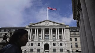 A woman walks in front of the Bank of England, at the financial district in London, 23 March, 2023.